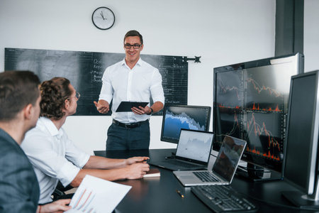 Conception of teamwork. Team of stockbrokers works in modern office with many display screens