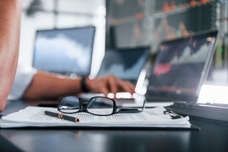 Close up focused view of glasses, notepad, documents and man at backgroundの写真素材