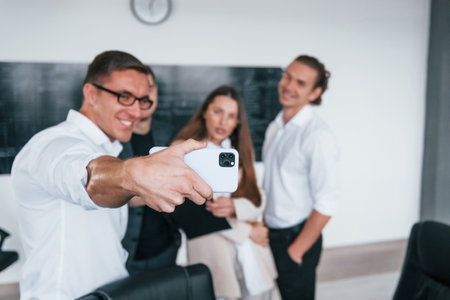 Making selfie. Group of young smart people that standing near blackboard in officeの写真素材
