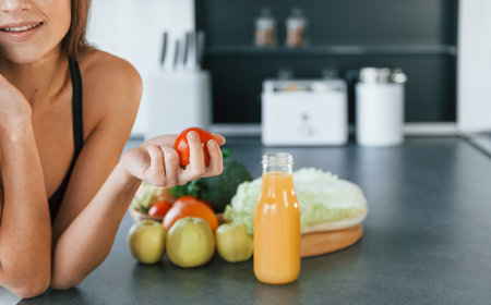 Talks by the phone. Young european woman is indoors at kitchen indoors with healthy foodの写真素材