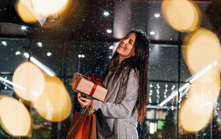Near the car with gift box. Cheerful woman is outdoors at Christmas holidays time. Conception of new yearの写真素材