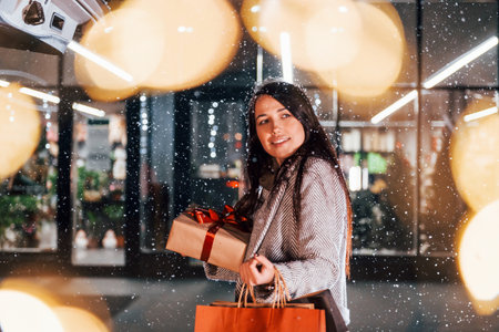 Near the car with gift box. Cheerful woman is outdoors at Christmas holidays time. Conception of new yearの写真素材
