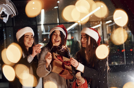 With Bengal lights. Three cheerful women spends Christmas holidays together outdoors. Conception of new yearの写真素材