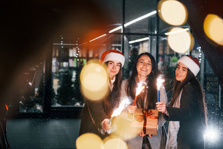 Little fireworks, Bengal lights. Three cheerful women spends Christmas holidays together outdoors. Conception of new yearの写真素材