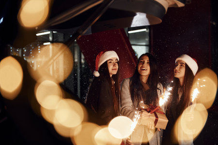 Little fireworks, Bengal lights. Three cheerful women spends Christmas holidays together outdoors. Conception of new yearの写真素材