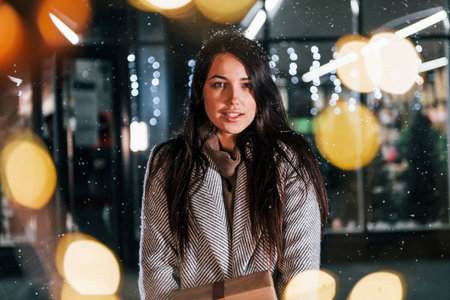 With present in hands. Cheerful woman is outdoors at Christmas holidays time. Conception of new yearの写真素材