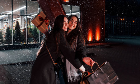 Walks with packages. Just from shopping. Happy sisters twins spends Christmas holidays together outdoors. Conception of new yearの写真素材