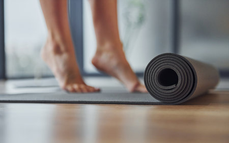Close up focused view on mat. Young woman in sportive wear and with slim body have fitness yoga day indoorsの写真素材