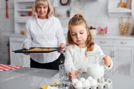 Finished product. Senior grandmother with her little granddaughter cooks sweets for Christmas on the...