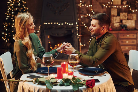 Holding by the hands. Young lovely couple have romantic dinner indoors togetherの写真素材