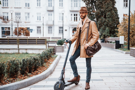 On the electric scooter. Young male model in fashionable clothes is outdoors in the city at daytimeの写真素材