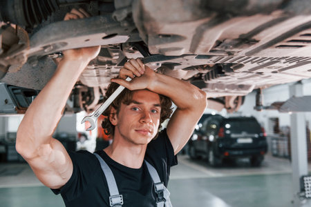 Handsome adult man in grey colored uniform standing below automobileの写真素材