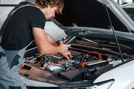 Tests cars electronics. Adult man in grey colored uniform works in the automobile salonの写真素材