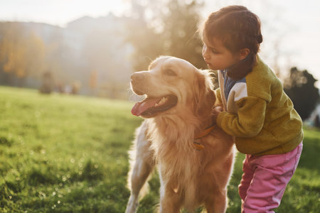 Little girl have a walk with Golden Retriever dog in the park at daytimeの写真素材