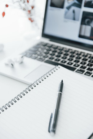 Close up view of notepad with pen on it and laptop at backgroundの写真素材