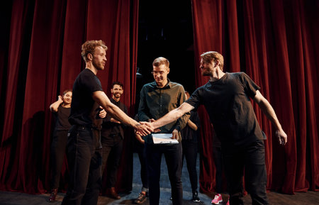 Working together. Group of actors in dark colored clothes on rehearsal in the theaterの写真素材