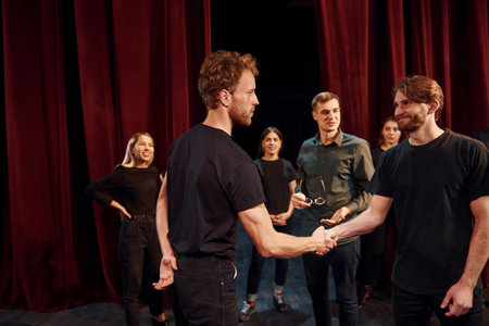Eye contact practice. Group of actors in dark colored clothes on rehearsal in the theaterの写真素材