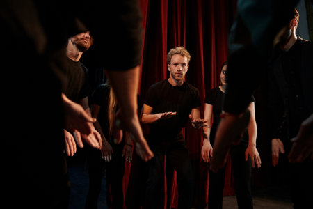 Practice in progress. Group of actors in dark colored clothes on rehearsal in the theaterの写真素材
