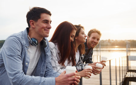 Coffee time. Group of young cheerful friends that is outdoors having fun togetherの写真素材