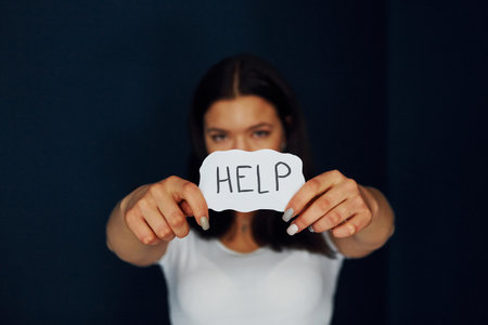 Young scared woman holds sign and ask for help. Conception of domestic violenceの写真素材