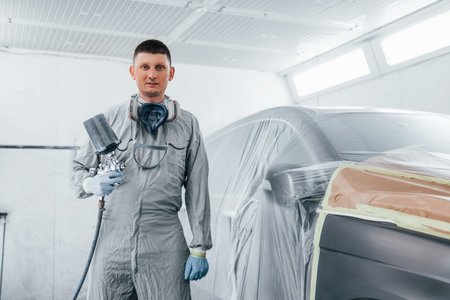 Caucasian automobile repairman in uniform works in garageの写真素材