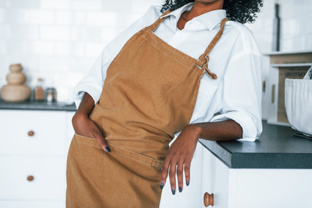 On the kitchen. Young african american woman with curly hair indoors at homeの写真素材