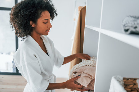 With different clothes. Young african american woman with curly hair indoors at homeの写真素材