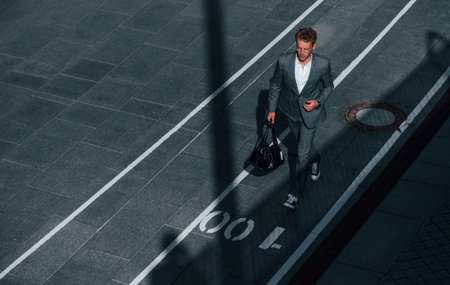 View from the top. Young businessman in grey formal wear is outdoors in the cityの写真素材