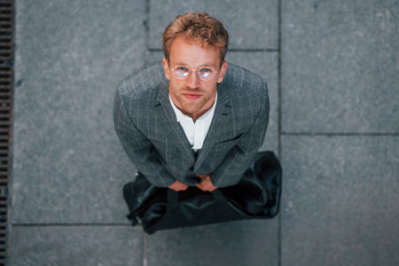 View from the top. Young businessman in grey formal wear is outdoors in the cityの写真素材