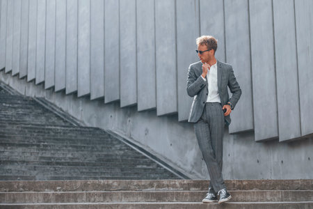 Posing for a camera. Young businessman in grey formal wear is outdoors in the cityの写真素材