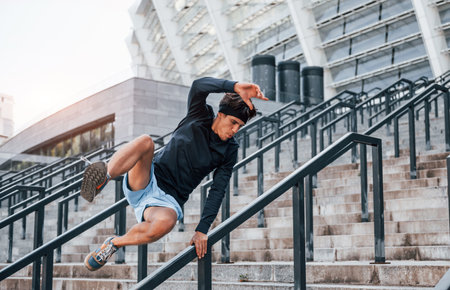 Does parkour. Young man in sportive clothes have workout outdoors at daytimeの写真素材