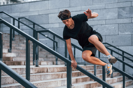 Jumps over obstacles. Young man in sportive clothes have workout outdoors at daytimeの写真素材