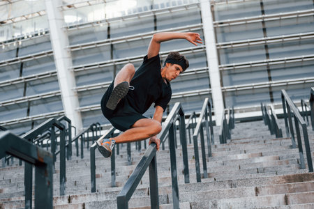 Does parkour. Young man in sportive clothes have workout outdoors at daytimeの写真素材
