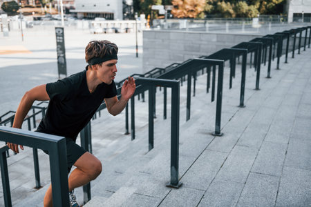 Young man in sportive clothes have workout outdoors at daytimeの写真素材