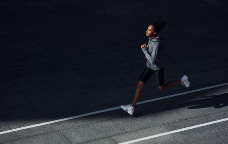 Fast runner. Young african american woman in sportive clothes have workout outdoors at daytime