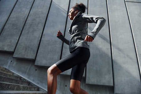 Fast runner. Young african american woman in sportive clothes have workout outdoors at daytimeの写真素材