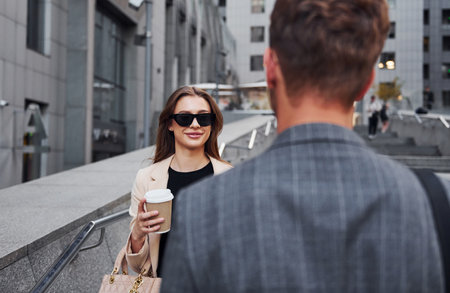 Girl holds drink. Woman and man in the town at daytime. Well dressed peopleの写真素材