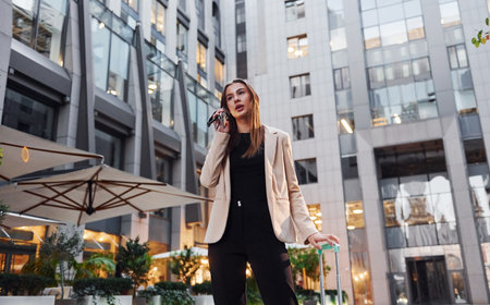 Town style clothes. Beautiful young european woman is outdoors in the city at daytimeの写真素材