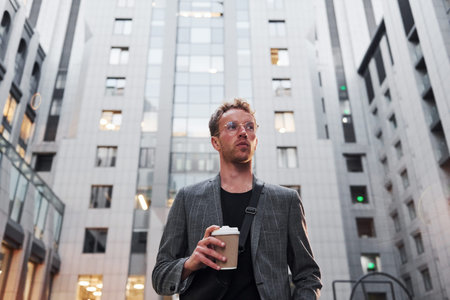 Young elegant man in good clothes is outdoors in the city at daytime