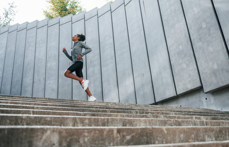 Young african american woman in sportive clothes have workout outdoors at daytime