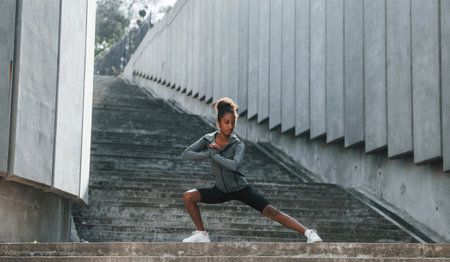 Young african american woman in sportive clothes have workout outdoors at daytimeの写真素材