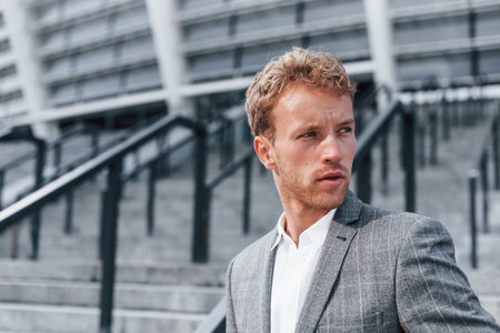 Young successful businessman in grey formal wear is outdoors in the cityの写真素材