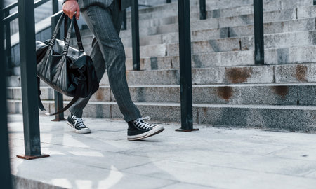 Close up view. Young successful businessman in grey formal wear is outdoors in the cityの写真素材
