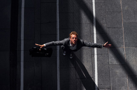 Celebrating success. Young businessman in grey formal wear is outdoors in the cityの写真素材