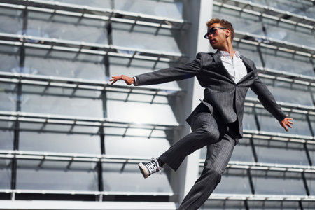 Celebrating success. Young businessman in grey formal wear is outdoors in the cityの写真素材