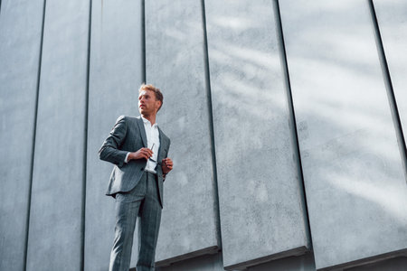 Sunny day. Young successful businessman in grey formal wear is outdoors in the cityの写真素材