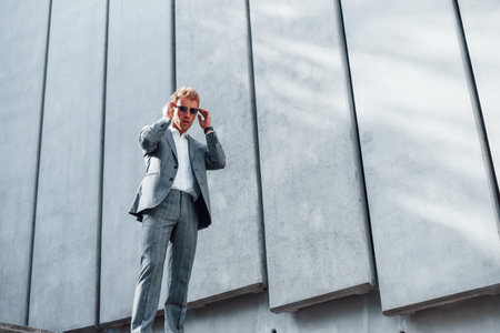 Sunny day. Young successful businessman in grey formal wear is outdoors in the cityの写真素材