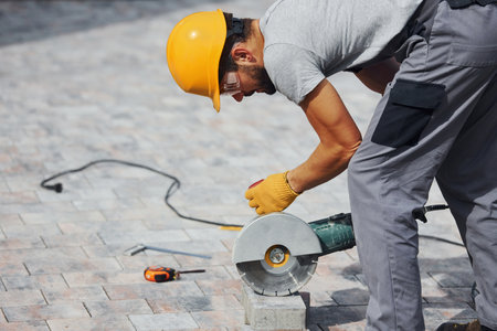 Concentrated at work. Man in yellow colored uniform have job with pavementの写真素材