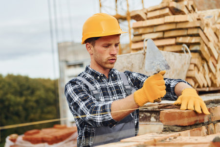 Laying bricks. Construction worker in uniform and safety equipment have job on buildingの写真素材