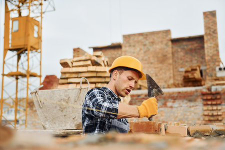 Laying bricks. Construction worker in uniform and safety equipment have job on buildingの写真素材
